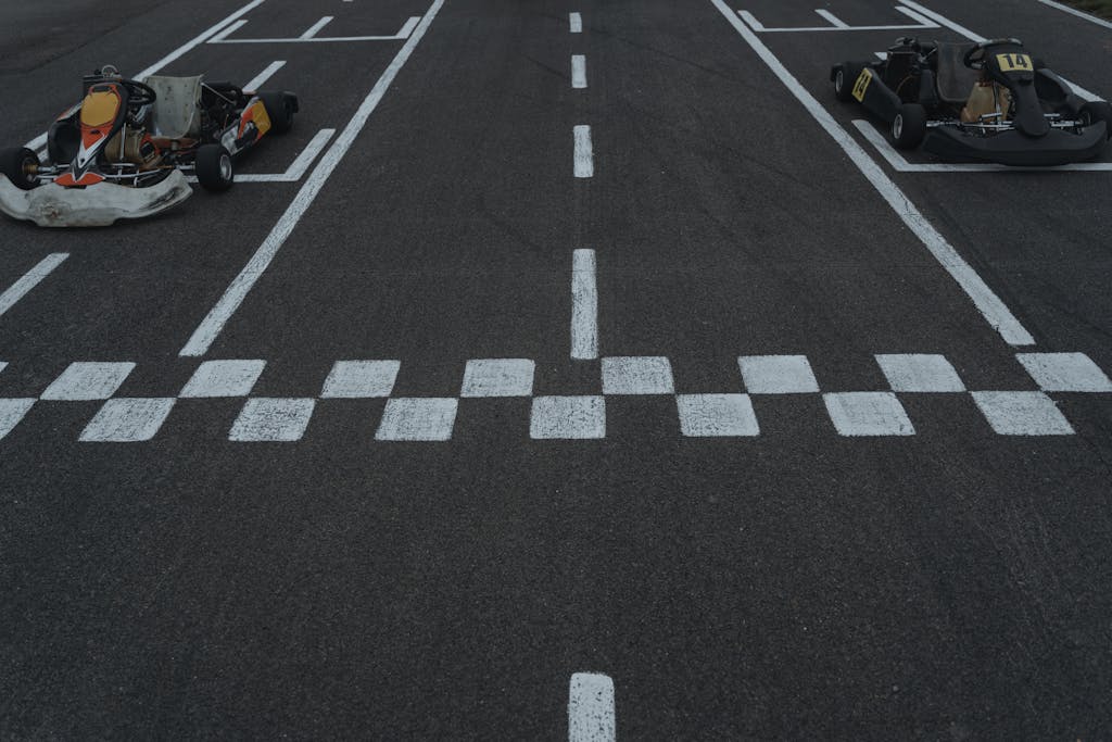 Two go-karts lined up at the starting grid on a motorsport track, ready for a race.